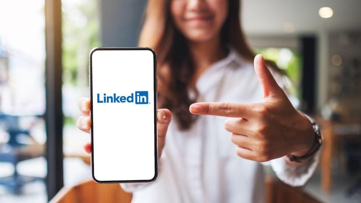 Jente holder fram smarttelefon med LinkedIn på