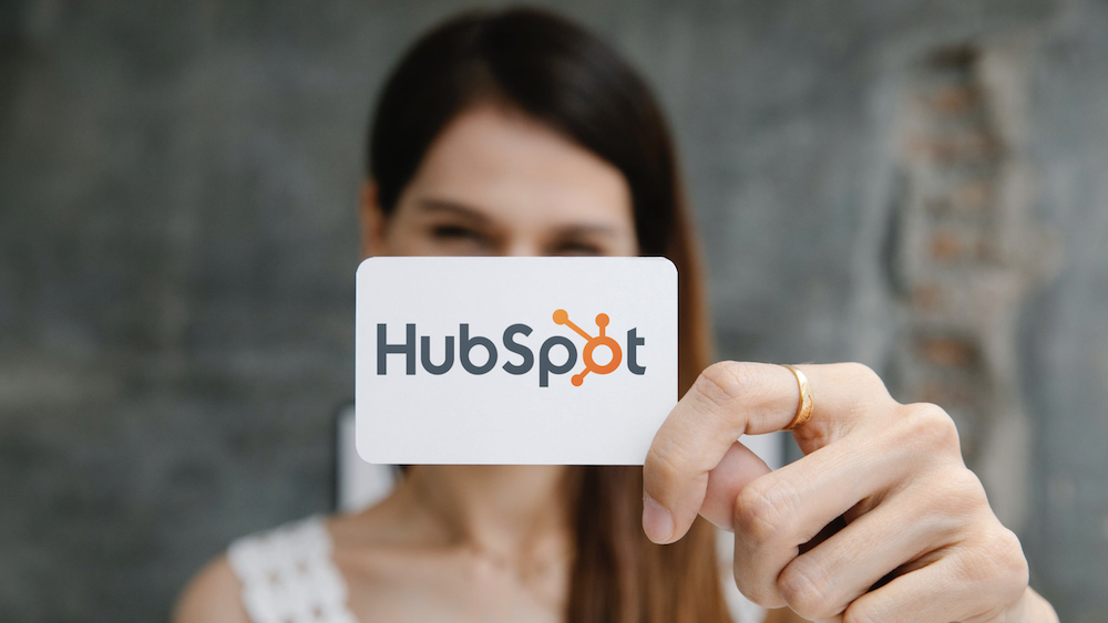 Ung kvinne holder et visittkort med HubSpot printet på baksiden