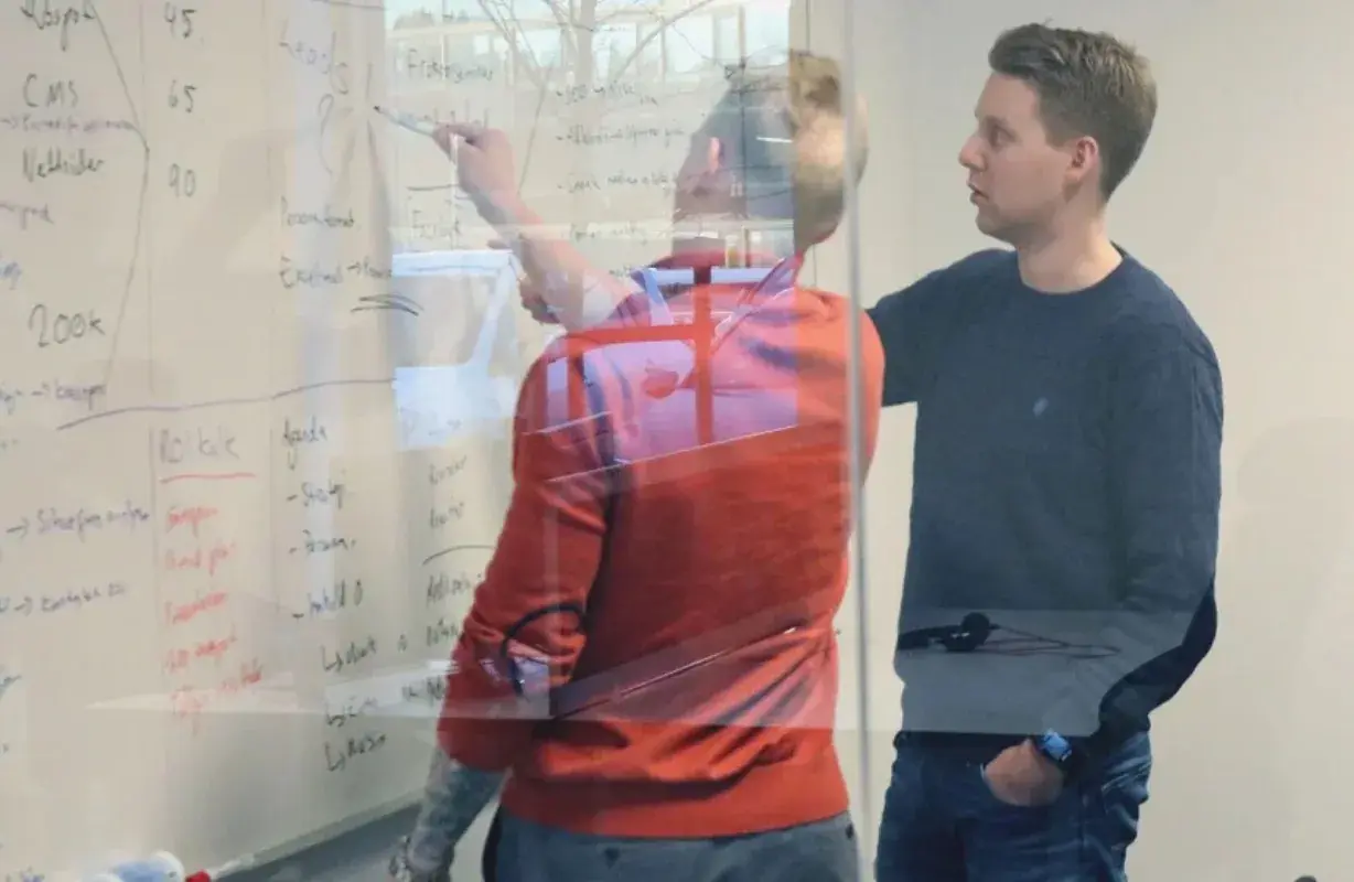 Techweb-tiden: to kolleger foran en glassvegg full av skisser og tall